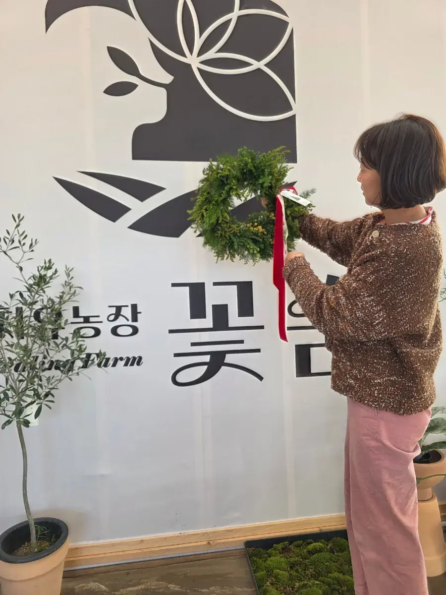 꽃숨 배너 앞에서 리스를 든 참가자