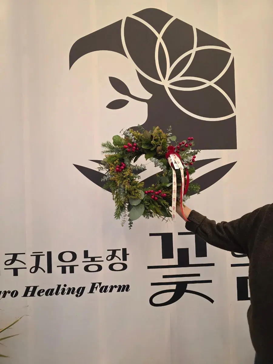 꽃숨 배너 앞에서 리스를 든 참가자